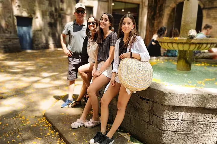 A group of tourists enjoying a sunny day by a historic fountain in Barcelona during a private city highlights tour.