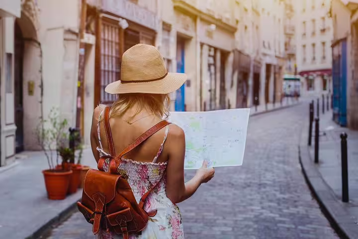 A woman explores a charming, sunlit street in Barcelona with a map, highlighting the allure of a private city tour for newcomers.