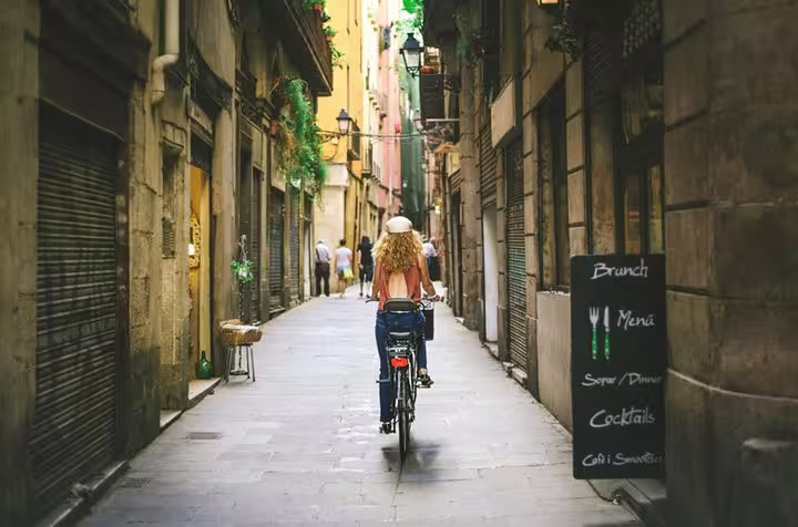 Cyclist explores narrow streets of Barcelona's vibrant Raval Quarter, showcasing local culture on a private walking tour.
