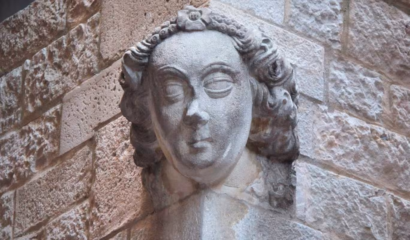 Detailed stone sculpture of a face on a medieval building wall in Barcelona's Ribera neighborhood.