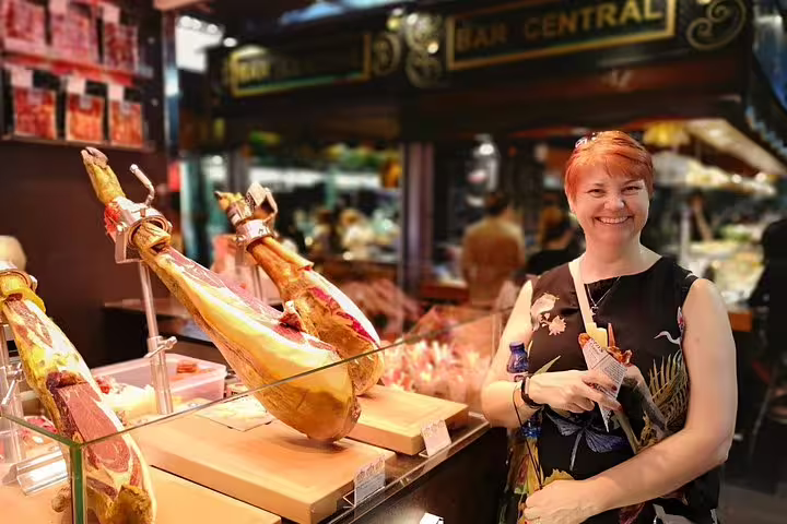 Smiling visitor enjoys local tapas at a vibrant Barcelona market during the Sagrada Familia and Park Guell private tour.