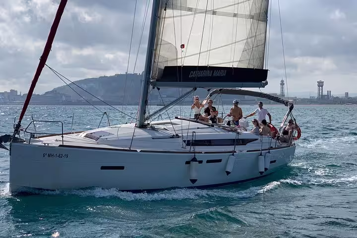 Group enjoying a scenic Barcelona sailing adventure with snacks and cava, cruising along the coast under a sunny sky.