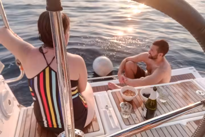 Couple relaxing on a Barcelona sailing tour at sunset with open bar, snacks, and swim stop from the yacht