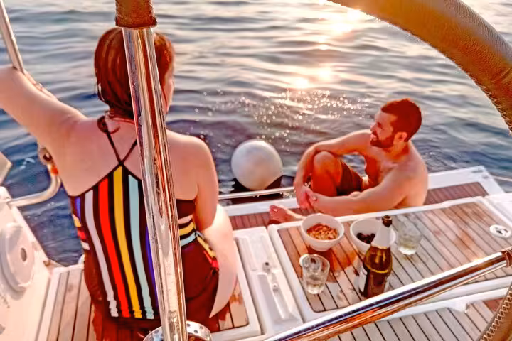 Couple enjoying snacks and drinks on a Barcelona sunset boat tour, relaxing on deck with open bar included