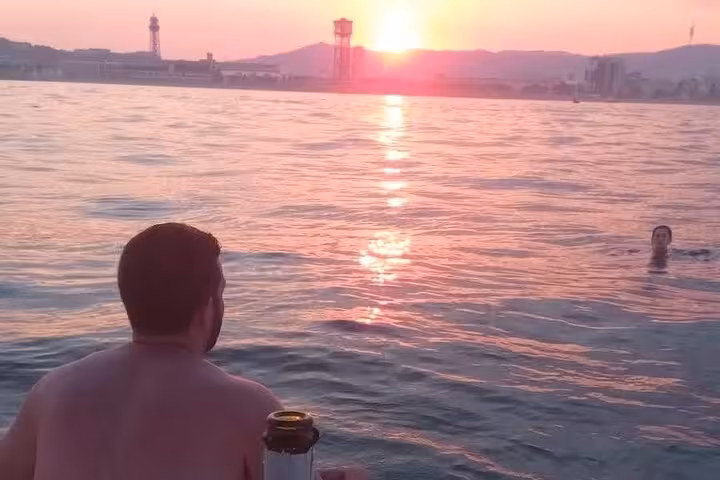 Swimmers enjoy Barcelona sunset cruise views with open bar drinks and snacks on the Mediterranean