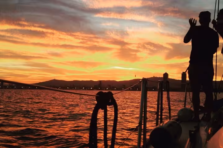 Silhouette of skipper at golden hour on Barcelona sunset cruise with open bar and snacks on the sea