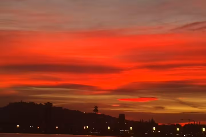 Vibrant red sunset sky over Barcelona coastline, seen on a private sailing tour with open bar and snacks