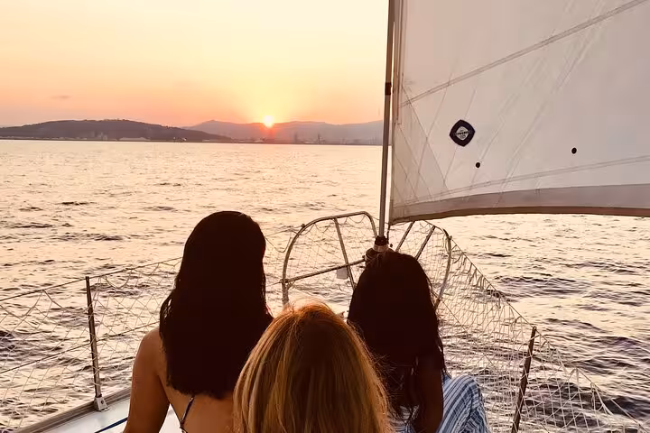 Guests relaxing on a private Barcelona sunset sailboat cruise, watching the sun set over the Mediterranean