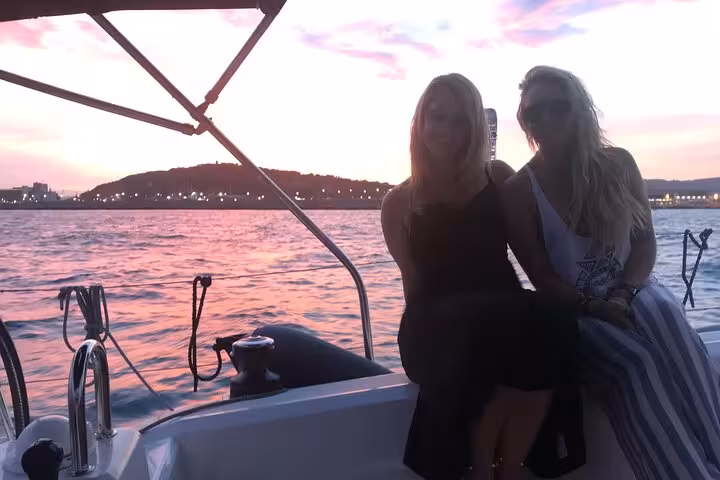 Two friends relaxing on a private Barcelona sunset sail with open bar and live Spanish guitar