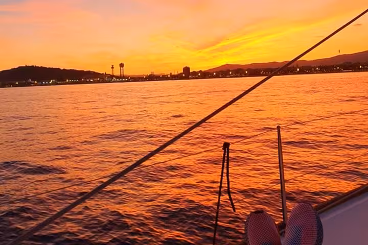 Golden Barcelona coastline at sunset from a private sailing boat, perfect for open bar guitar cruise