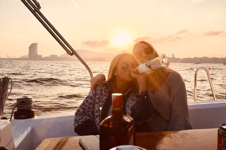 Friends enjoying open-bar drinks on a private Barcelona sunset sailing cruise with sea views and snacks