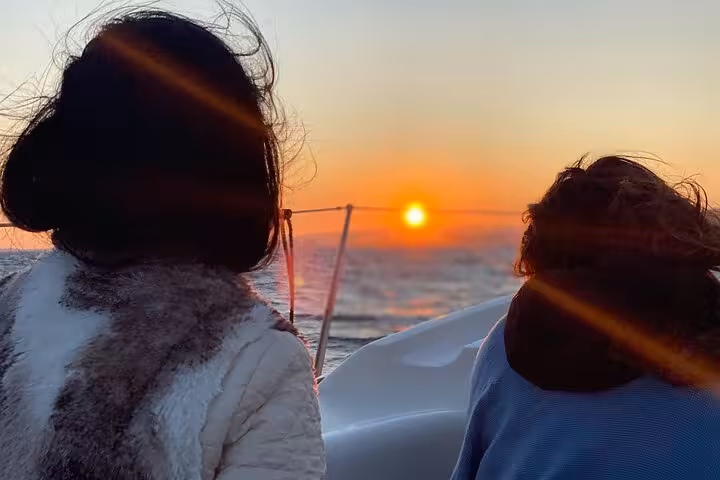 Guests watch the sun set from a private sailboat in Barcelona, with open bar and snacks onboard