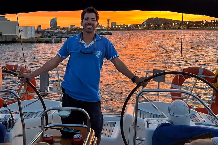 Skipper at the helm on a Barcelona sunset private sailing tour with open bar, snacks, and skyline views