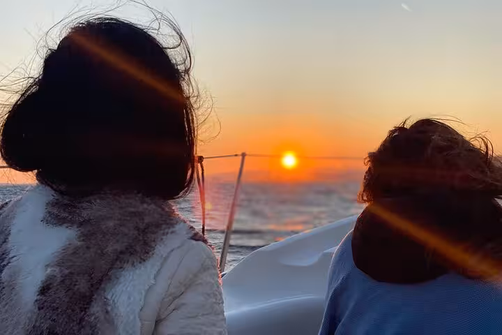 Couple watching the sun set at sea on Barcelona sunset tour, open bar and snacks aboard the boat