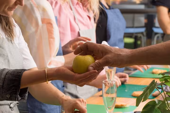 Instructor handing a fresh tomato to a participant in a Barcelona tapas cooking class.
