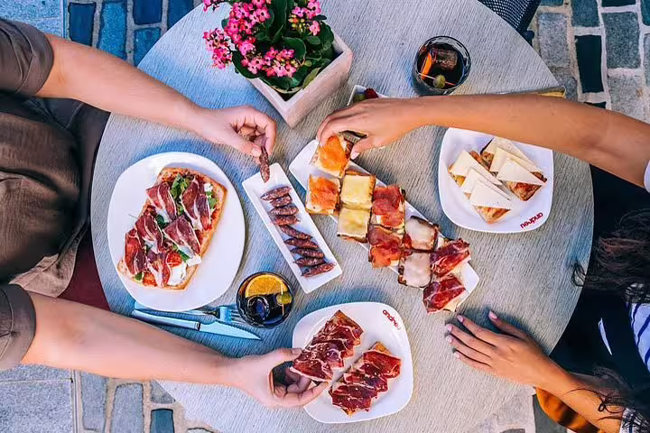 Aerial view of people enjoying traditional Spanish tapas in Barcelona, featuring Iberian ham and refreshing drinks.