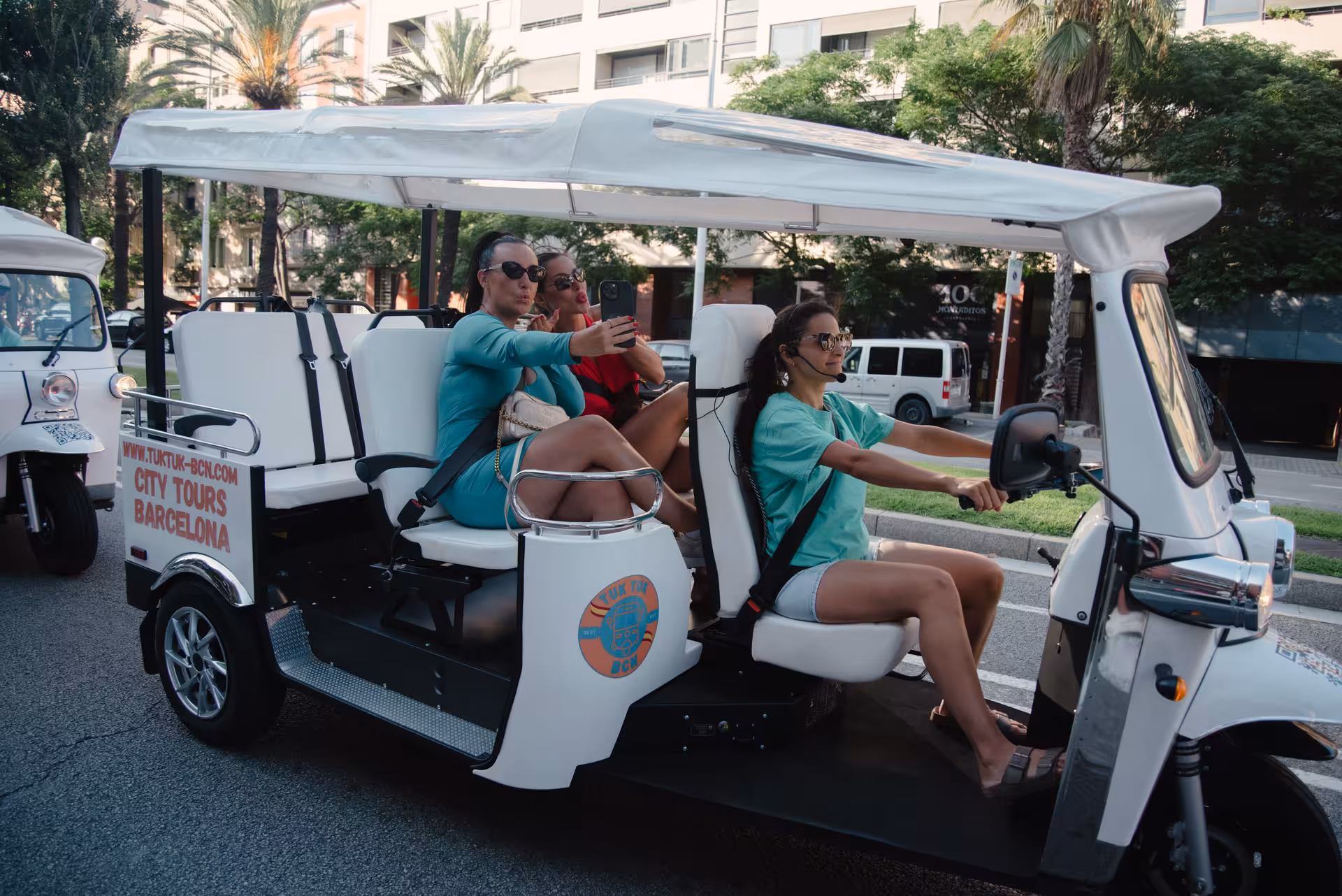 Guests sightseeing in an electric tuk tuk on the Regular Barcelona tour, cruising past palm-lined avenues