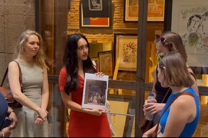 Guide shows artwork to group on Barcelona walking tour, enhancing cultural experience.