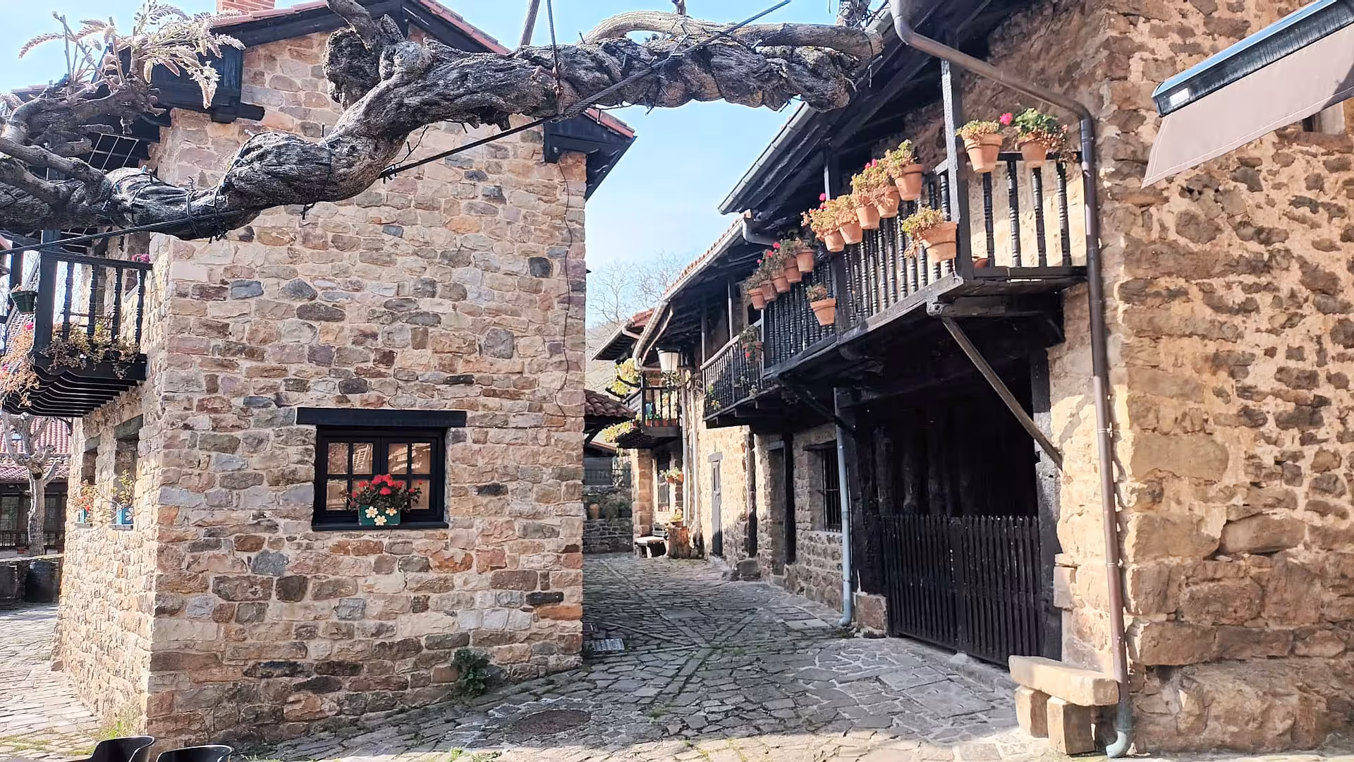 Charming cobblestone street with rustic stone buildings and flower-filled balconies in Barcena Mayor Cantabria Spain
