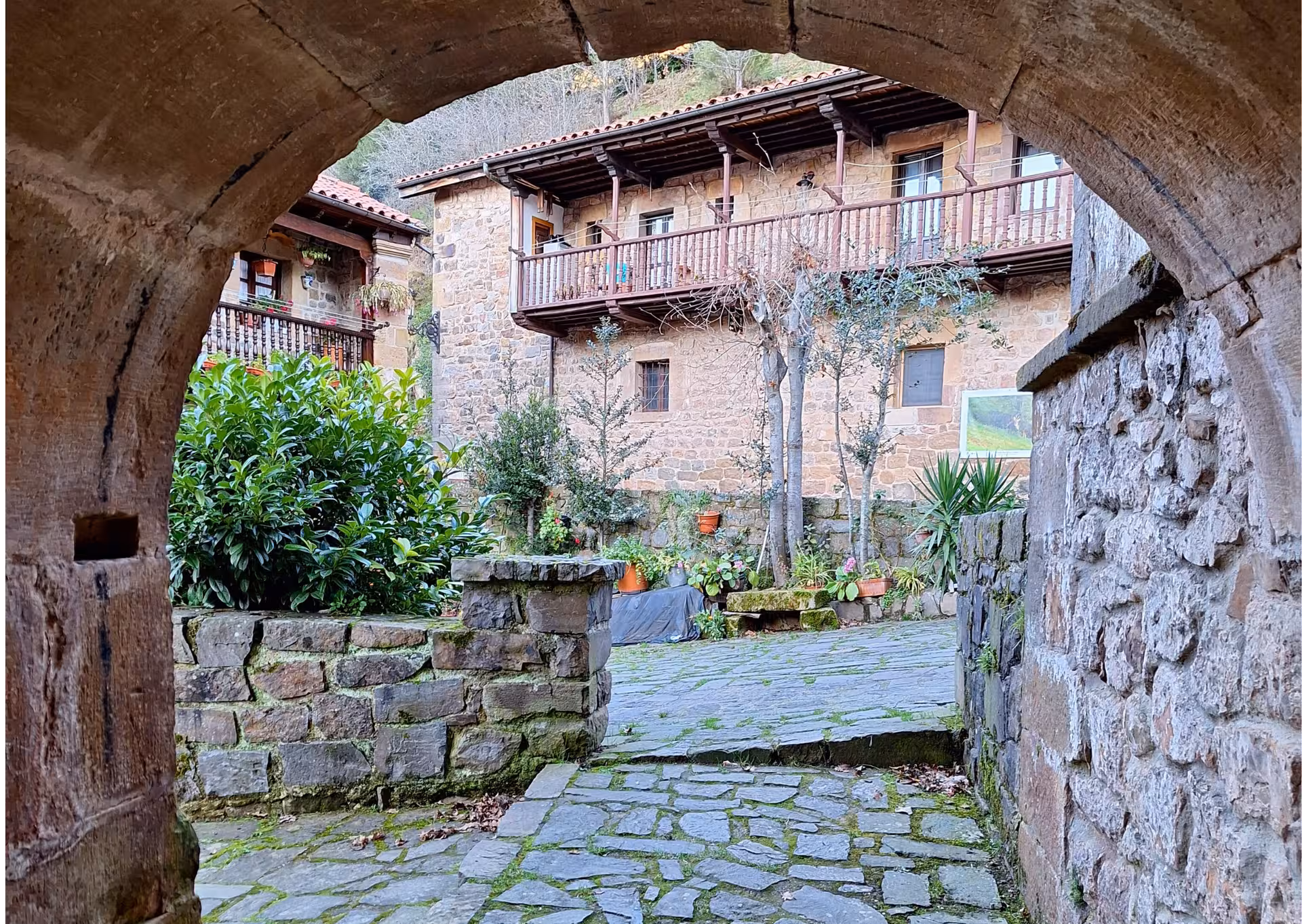 Stone arch gateway leading to a charming cobblestone courtyard in Barcena Mayor Cantabria village day trip