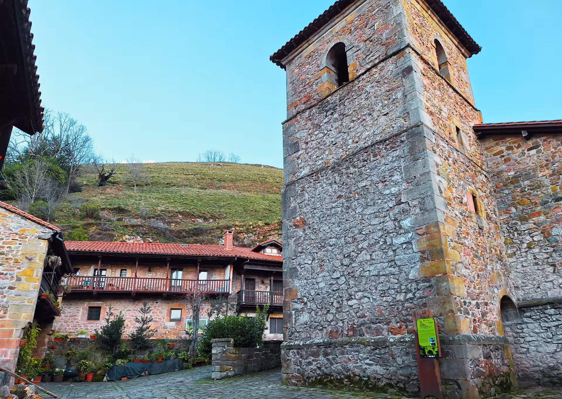 Historic stone church bell tower and traditional Cantabrian stone house in Barcena Mayor village Spain