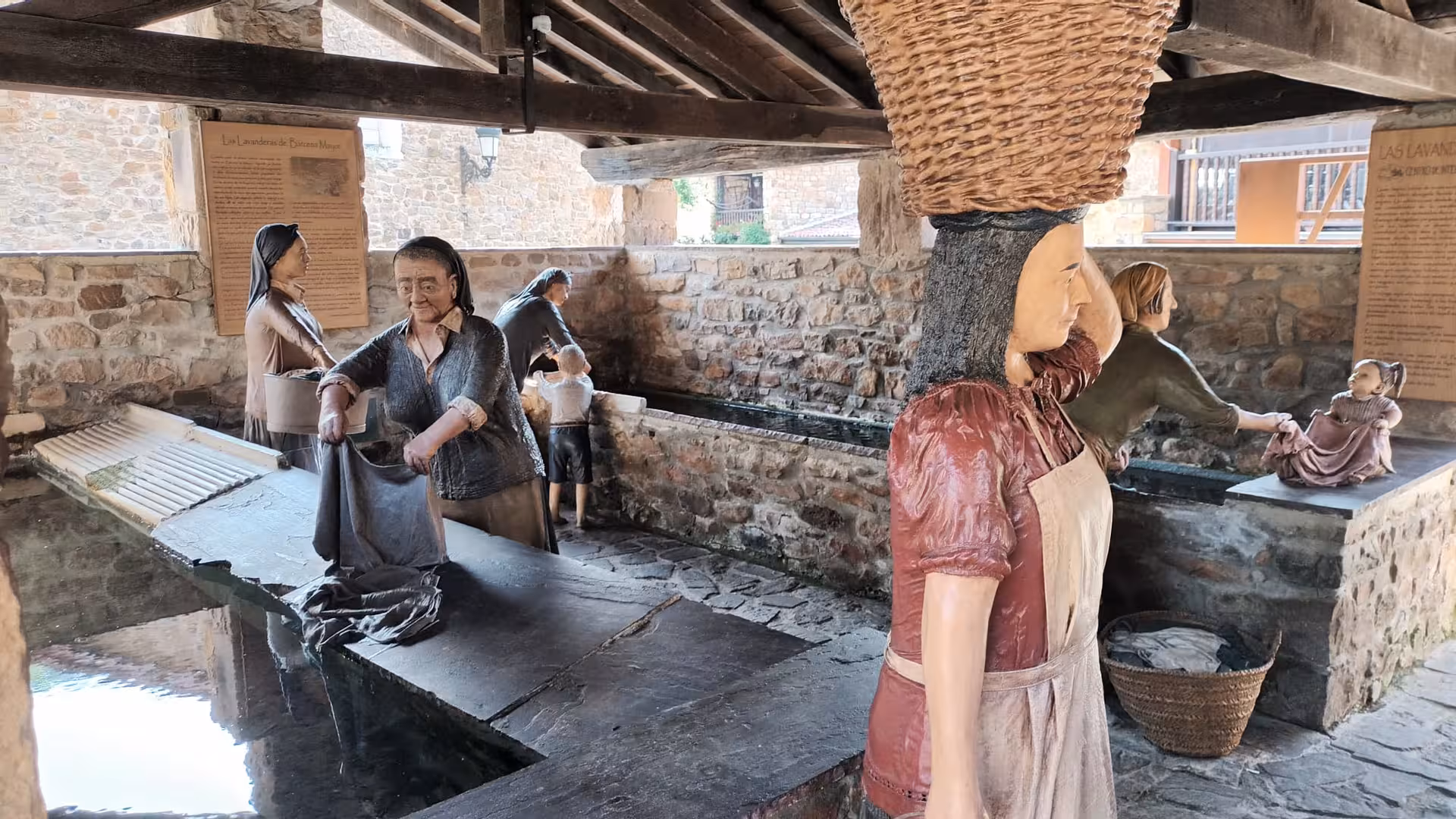 Traditional laundry sculptures depicting village women washing clothes at historic washhouse in Bárcena Mayor Cantabria