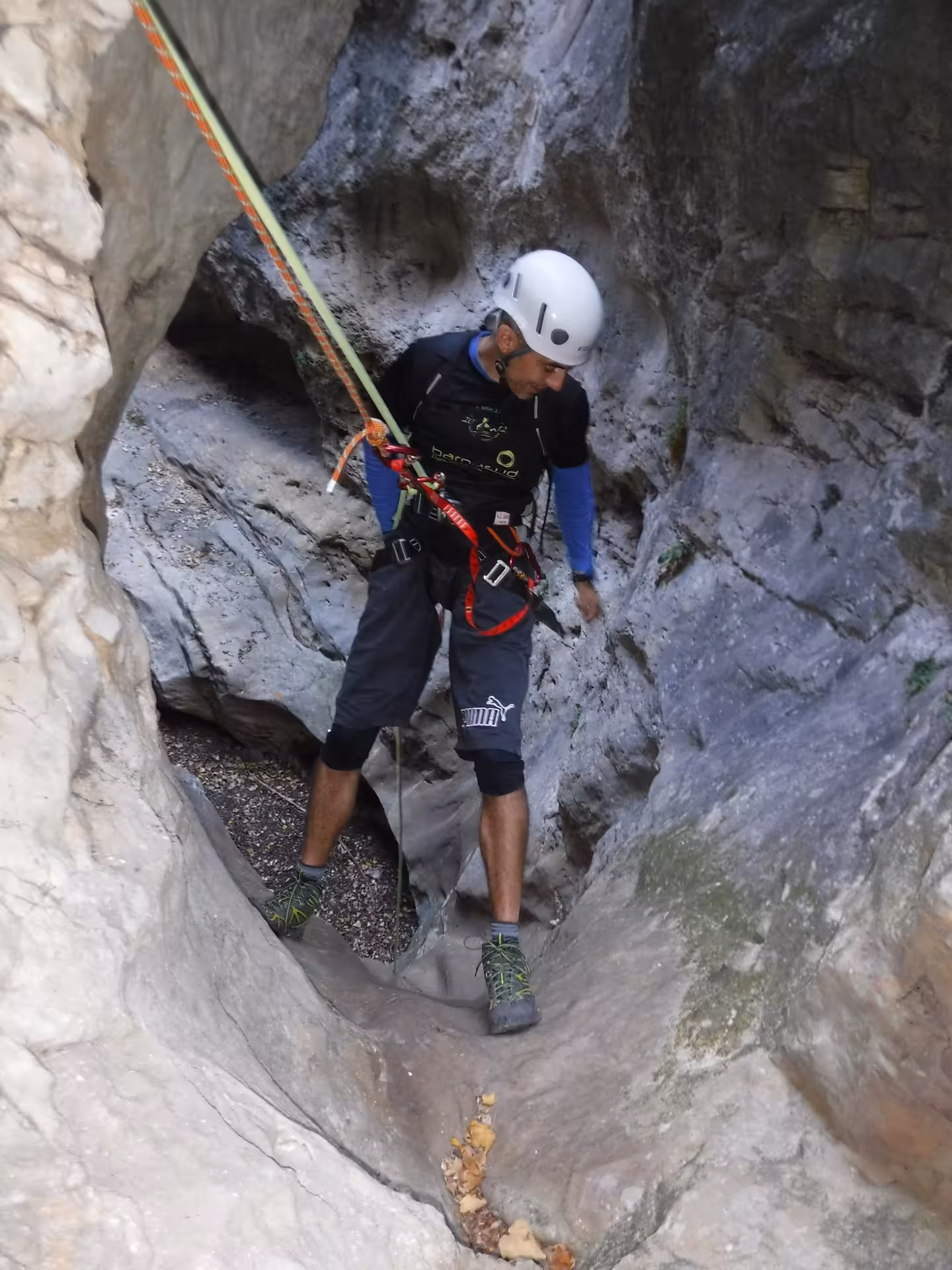 Barranquista con casco y arnés desciende con cuerda por una estrecha garganta del barranco seco de Aliaga, Teruel
