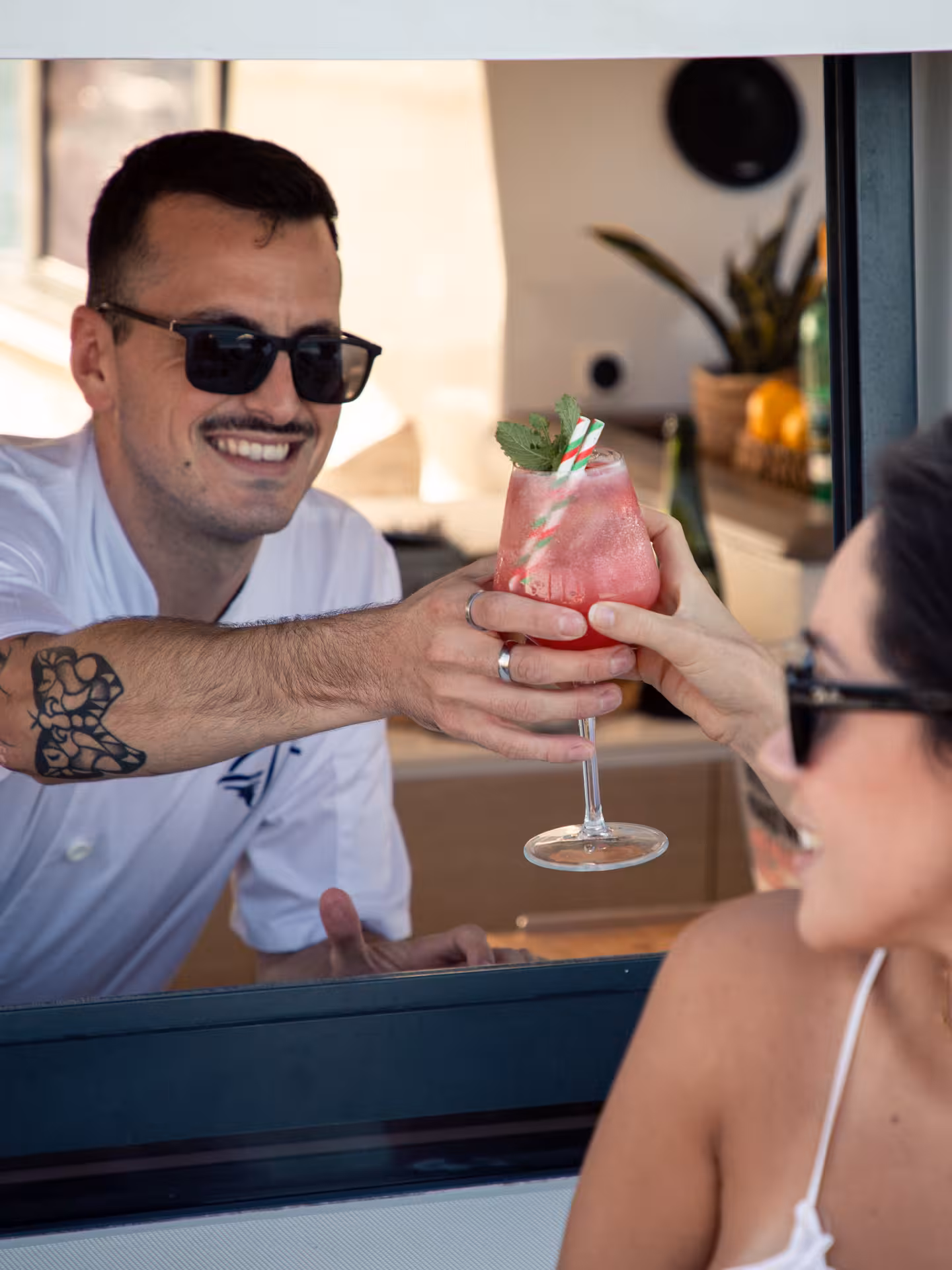 Bartender serves a pink cocktail with mint garnish to a guest, showcasing interactive cocktail masterclass experience