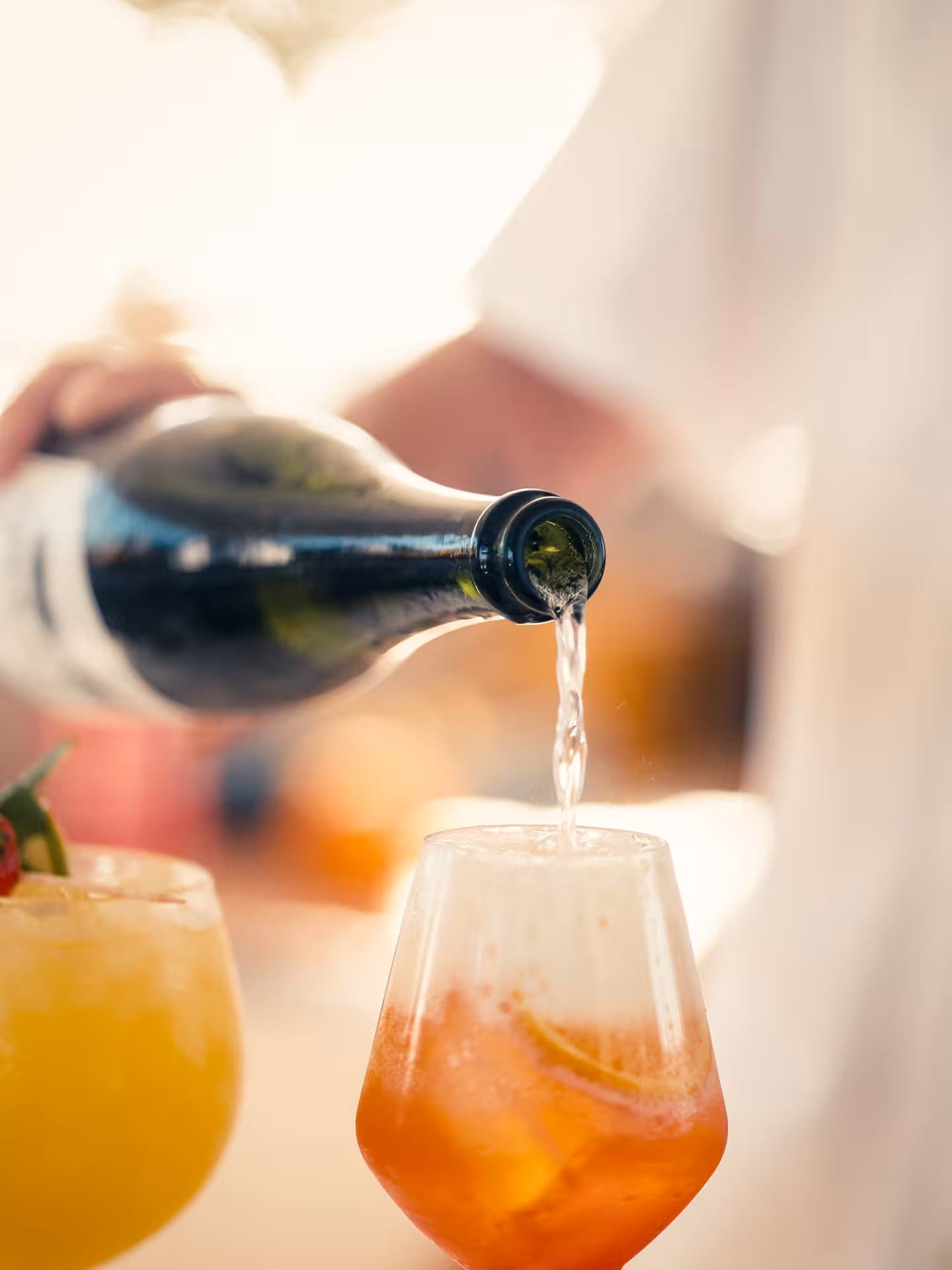 Bartender pouring sparkling wine into an Aperol spritz during a cocktail masterclass mixology experience