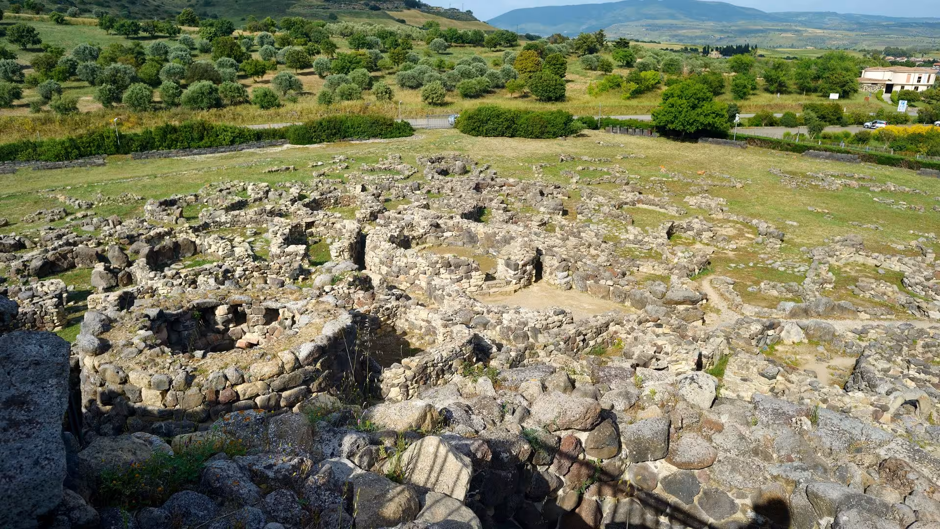 Explore the ancient stone ruins of the UNESCO archaeological site of Barumini surrounded by lush Sardinian landscapes.