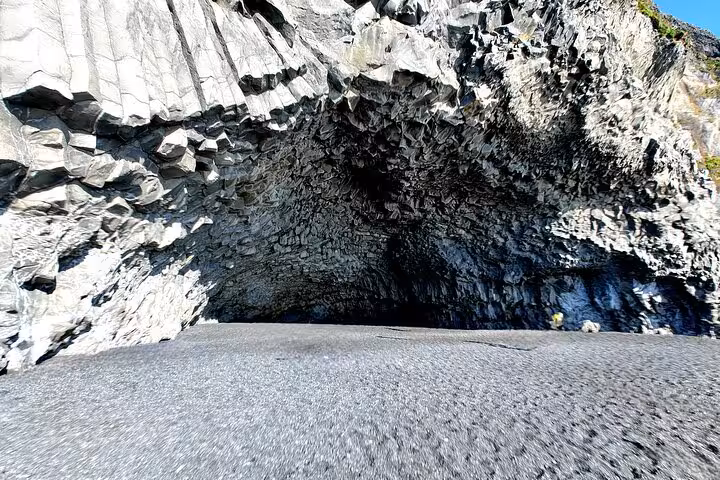 Black basalt rock cave with volcanic columns on Iceland's South Coast black sand beach