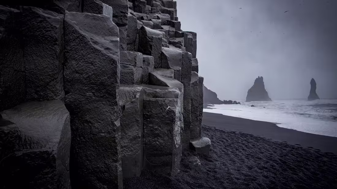 Basalt rock cliffs on a black sand beach