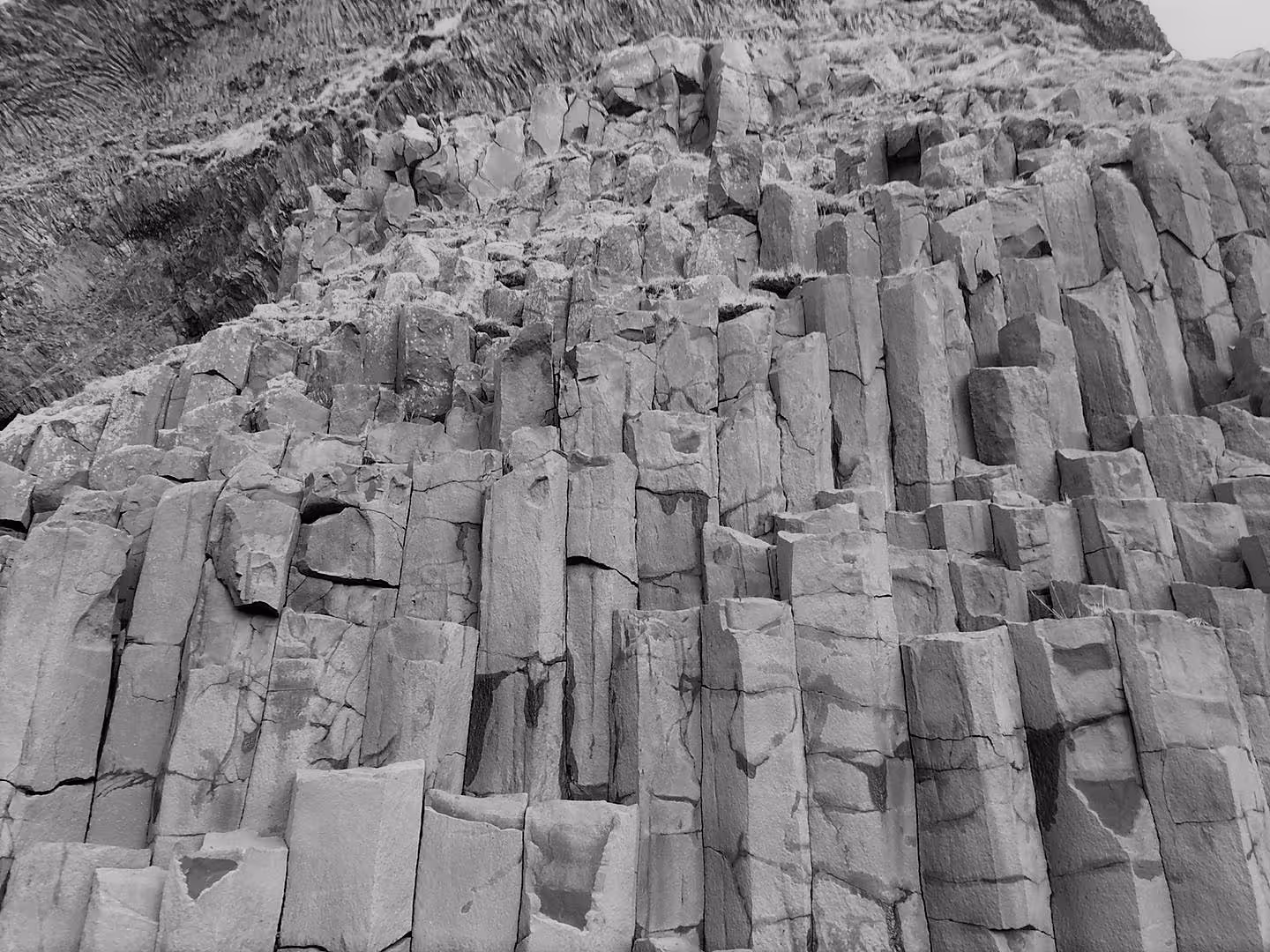 Dramatic basalt rock columns on Iceland's South Coast cliff face in black and white