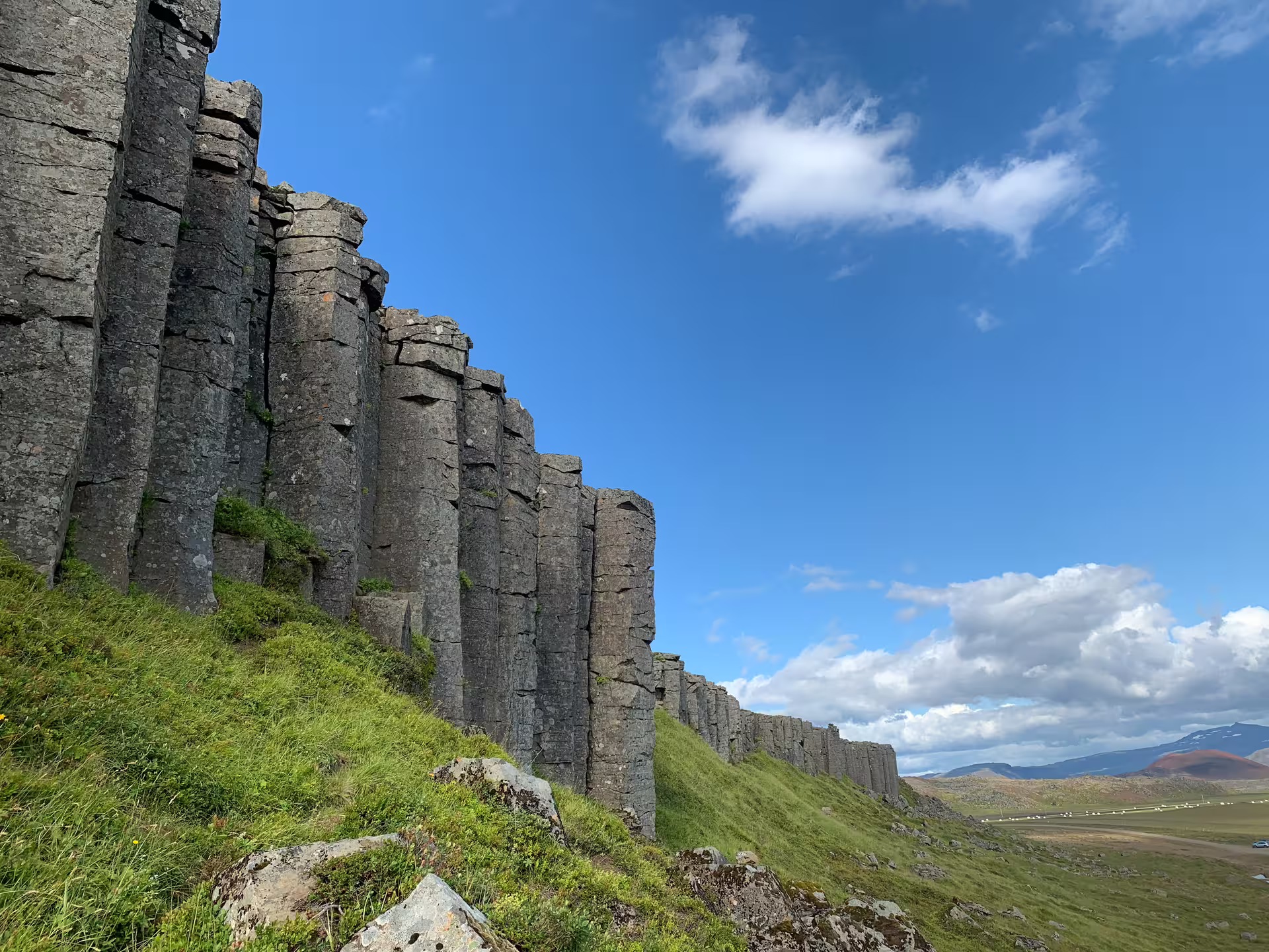 Tall basalt rock columns rising above green hillside on Snaefellsnes Peninsula, Iceland