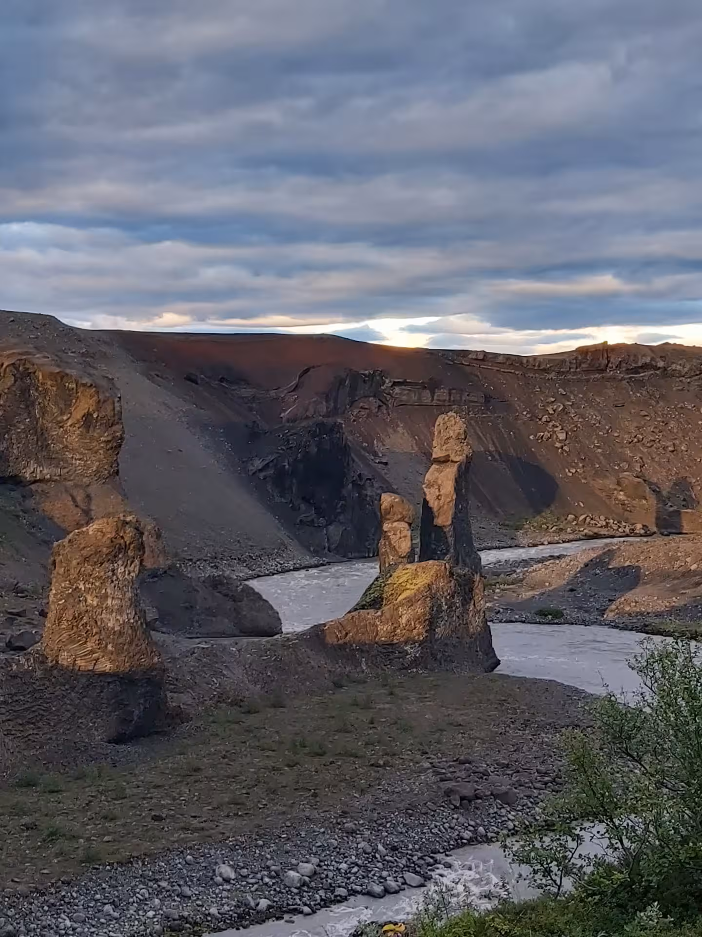 Tall basalt rock formations along a glacial river in a volcanic canyon in North Iceland