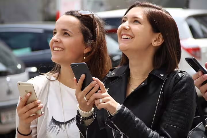 Two travelers smiling with smartphones on a Basel scavenger hunt and sights self-guided walking tour
