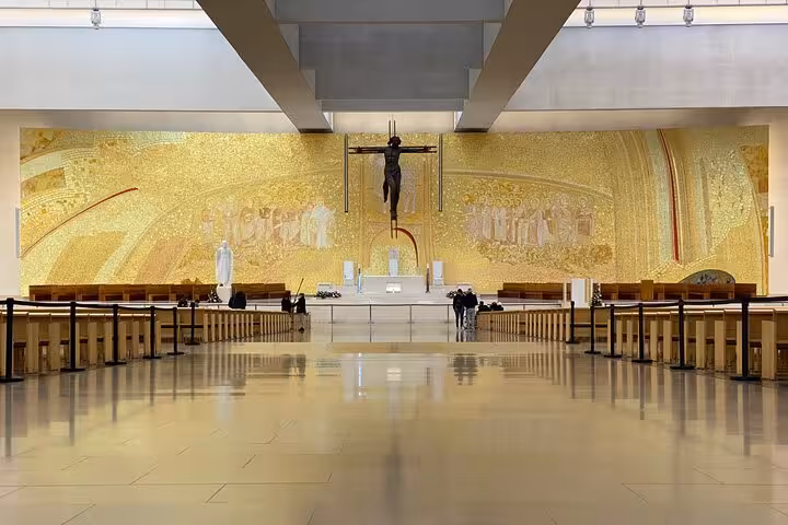 Interior view of the Basilica of the Holy Trinity in Fatima, featuring a golden mosaic and modern architectural design.