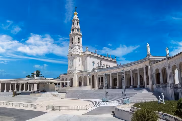 The stunning Basilica of Our Lady of the Rosary in Fátima under a clear blue sky, featured in a Lisbon day tour.