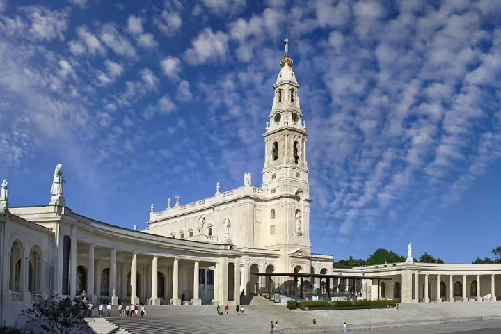The Basilica of Our Lady of the Rosary in Fátima, Portugal, under a vibrant sky, is a key stop on religious tours.