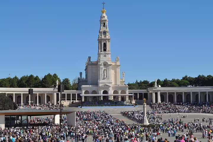 "View of the Basilica of Our Lady of the Rosary in Fatima with a large gathering of visitors, featured in a Private Tour of Fatima, Nazareth, and Óbidos. Experience Portugal's religious and historical landmarks on an exclusive guided tour."