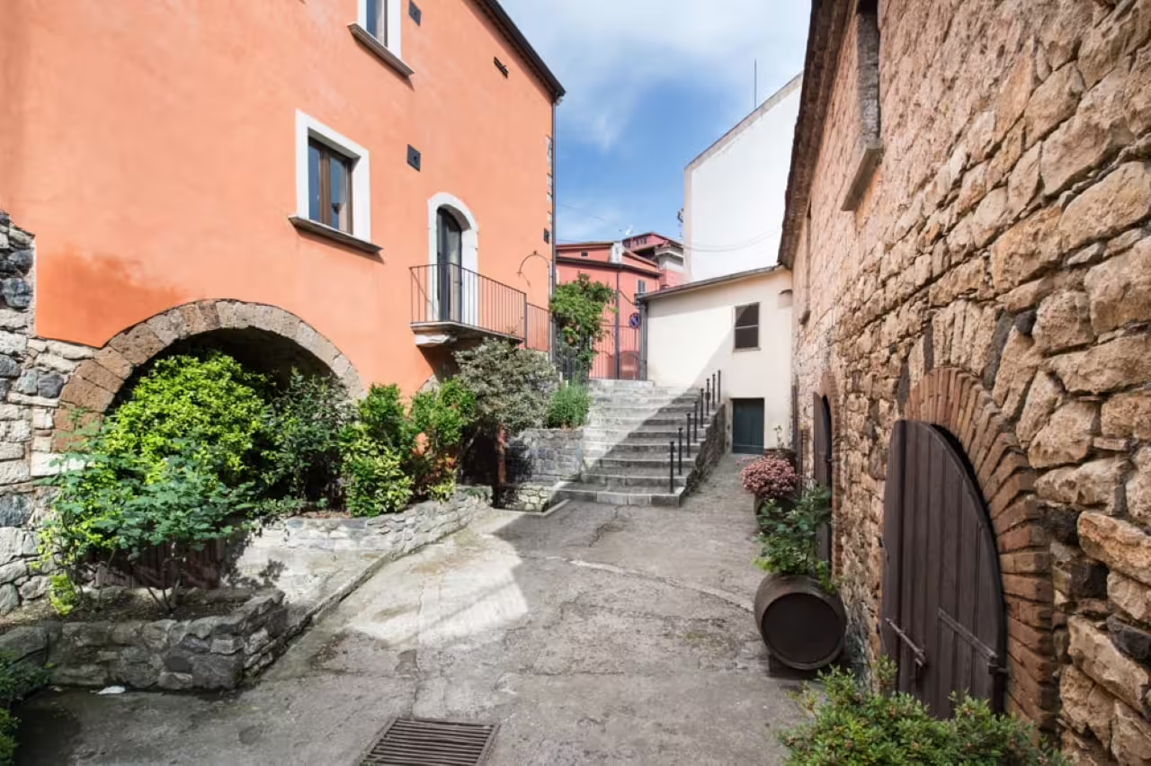 Historic Basilicata village alley with stone arches and stairs, gateway to volcanic tuff cave tour and wines