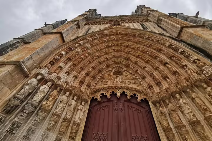 Gothic arch of Batalha Monastery in Portugal, showcasing intricate stone carvings, part of a full-day private tour from Lisbon.