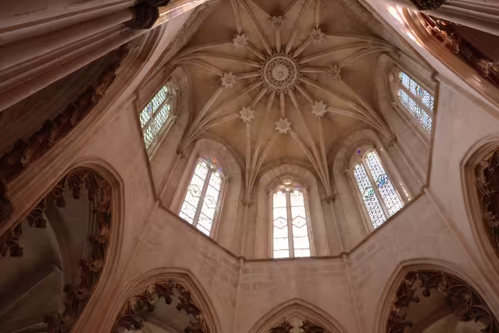 Intricate Gothic ceiling and stained glass windows of Batalha Monastery, featured in private tour of Tomar, Fátima, and Batalha.