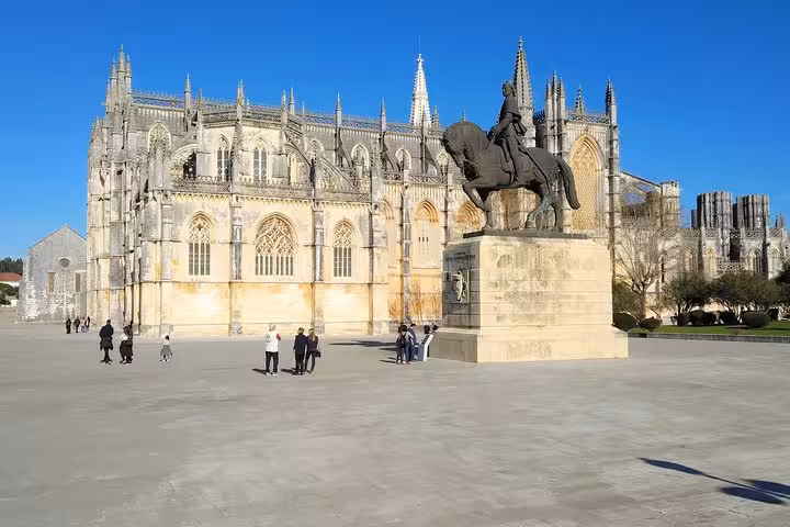 Batalha Monastery with equestrian statue, showcasing Gothic architecture on a sunny day for private tours.
