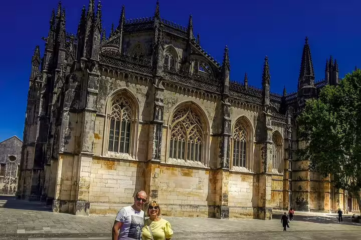 Tourists enjoying a sunny day outside the historic Batalha Monastery on a full-day private tour from Lisbon to Óbidos, Nazaré, Alcobaça, Batalha, and Fátima.