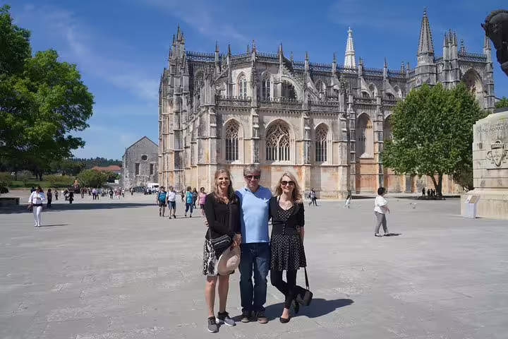 Tourists enjoying a sunny day at the stunning Batalha Monastery during a private full-day tour from Lisbon.