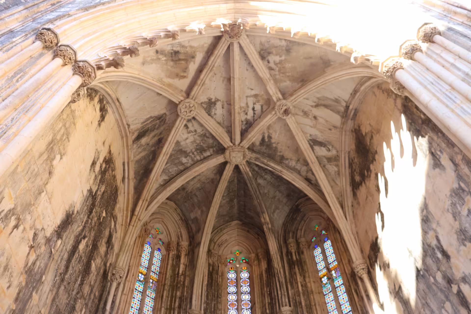 Intricate vaulted ceiling with stained glass windows at Batalha Monastery, featured in Tomar, Fátima, and Batalha private tour.
