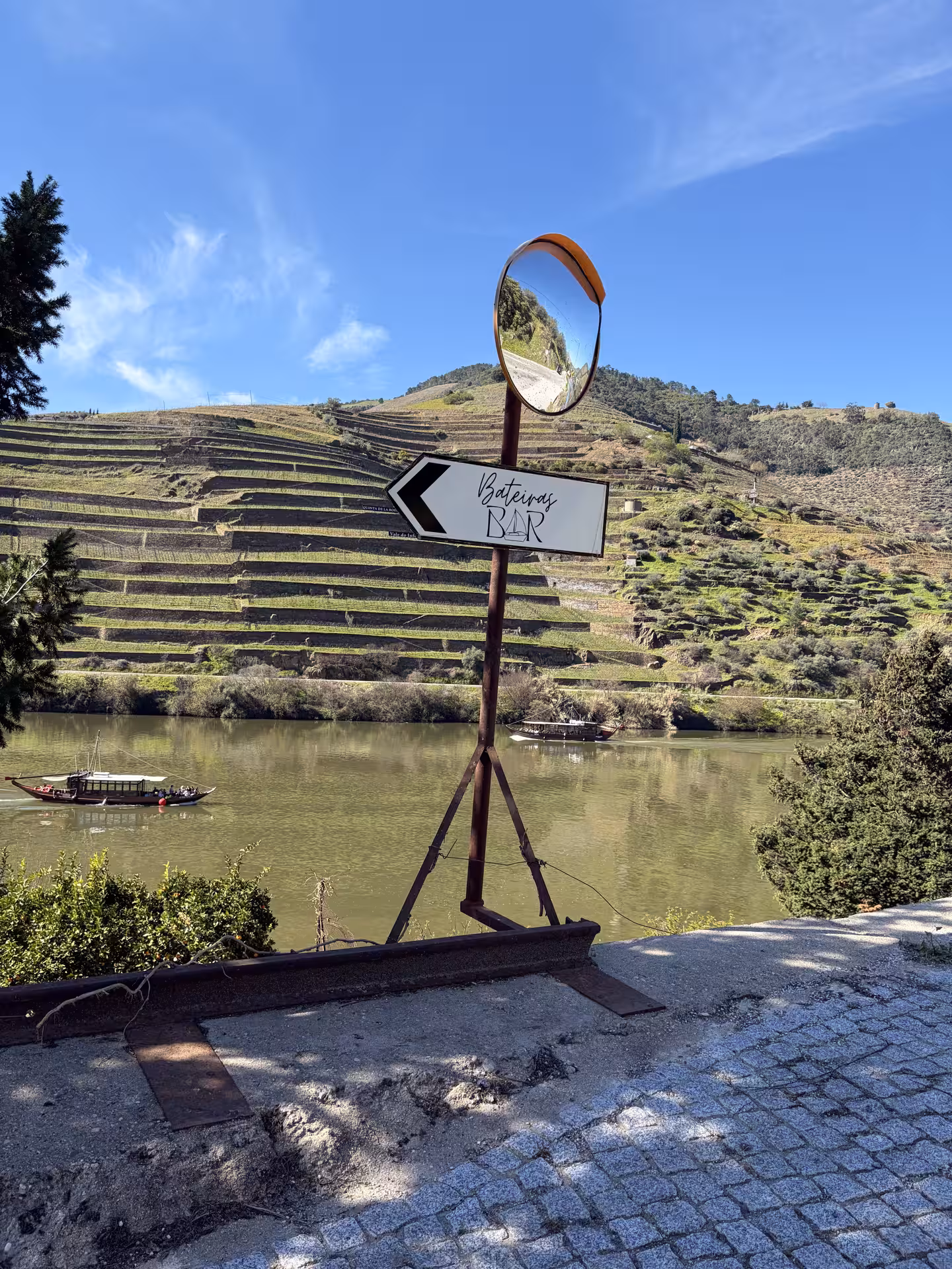 Bateiras Bar sign with terraced Douro Valley vineyards and river boats visible during a private 1h50 Douro River cruise tour