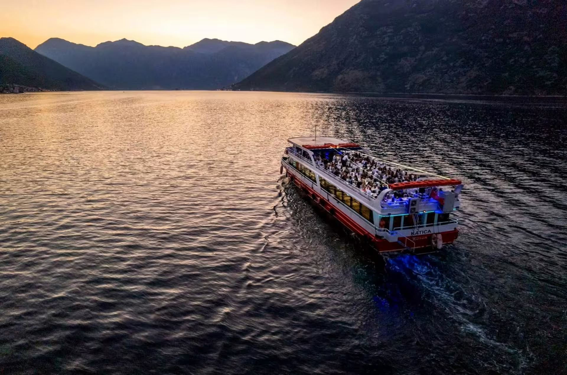 Sunset Bay of Kotor cruise from Dubrovnik with passengers on deck, Montenegro mountains and calm Adriatic waters