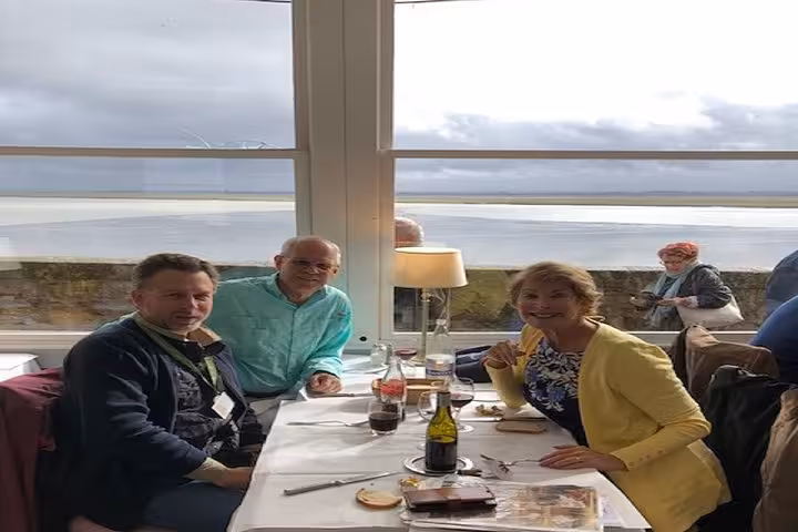 Three tourists dining with ocean view at restaurant during private day trip from Bayeux